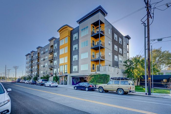 Contemporary urban apartment building with vibrant accents and spacious balconies in a bustling neighborhood setting.