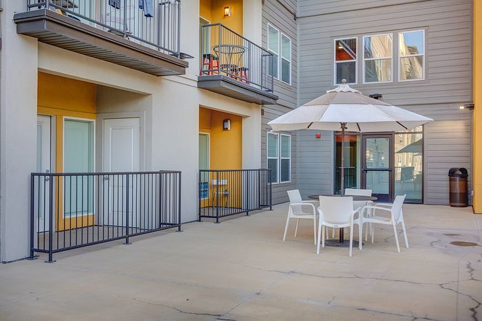 Charming apartment patio showcasing stylish outdoor seating and a modern facade, perfect for relaxation.