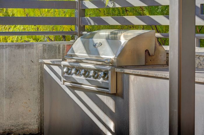 Sleek outdoor stainless steel grill on a sunny patio, perfect for summer BBQs and entertaining.