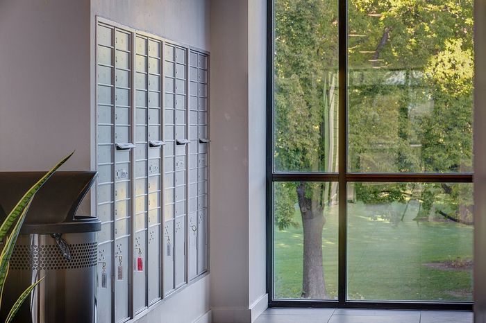 Modern apartment mailroom with sleek lockers and a large window showcasing a lush, green landscape.