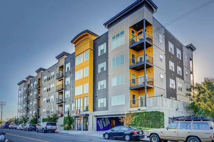 Modern five-story apartment building with vibrant yellow accents, offering spacious balconies and ample natural light.