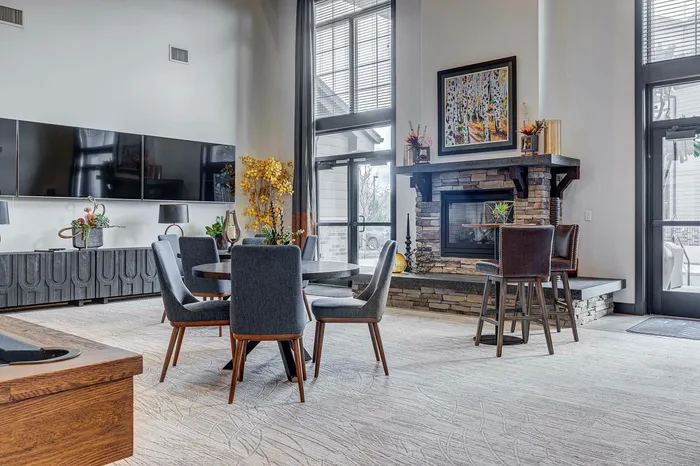 Elegant living room featuring stylish gray chairs, a modern stone fireplace, and large windows for abundant natural light.