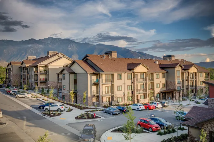 Charming residential complex surrounded by picturesque mountains, featuring modern architecture and ample parking.
