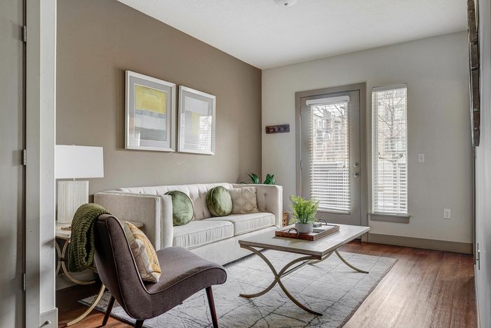 Elegant living room with modern decor, featuring a plush white sofa, chic coffee table, and abundant natural light.