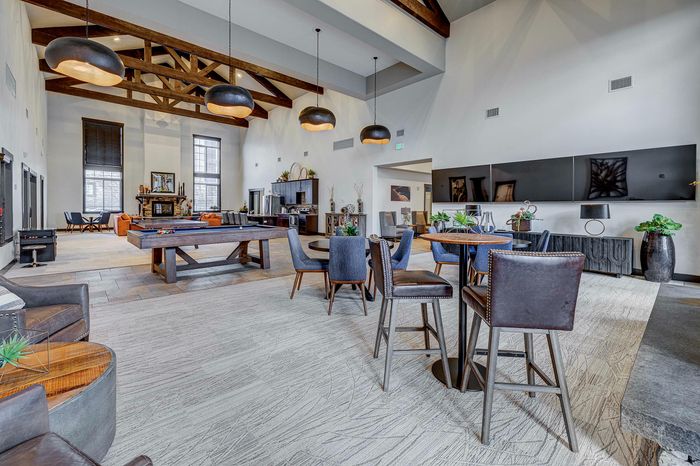 Luxurious community lounge featuring high ceilings with wooden beams, stylish modern seating, and a pool table.