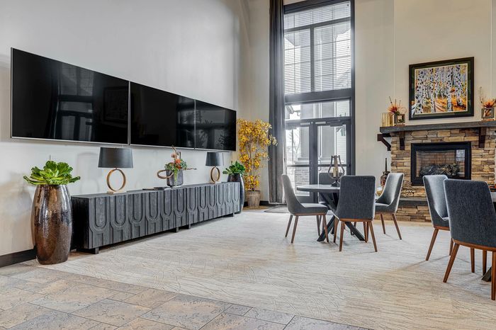 Luxurious living room with a modern stone fireplace, elegant dining area, and chic decor, featuring large windows for abundant natural light.