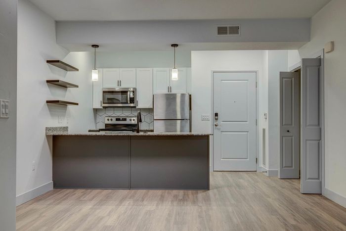 Modern kitchen with sleek stainless steel appliances, chic pendant lighting, and stylish open shelving, accentuating a bright and welcoming space.