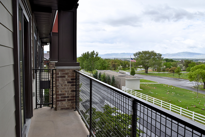 Charming balcony with modern railings offering scenic views of lush green landscape and mountains.
