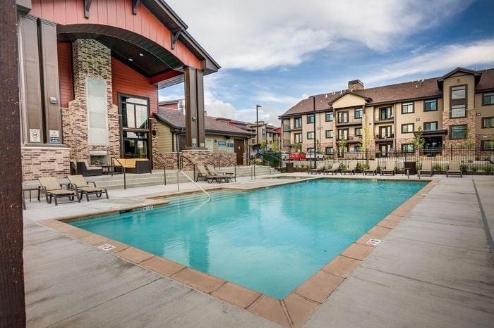 Luxurious apartment complex with a sparkling pool, modern architecture, and comfortable lounging area, perfect for relaxation and entertainment.