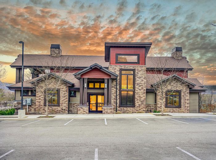 Charming modern building with brick facade and large windows, set against a captivating sunset backdrop, offering a warm and inviting atmosphere.