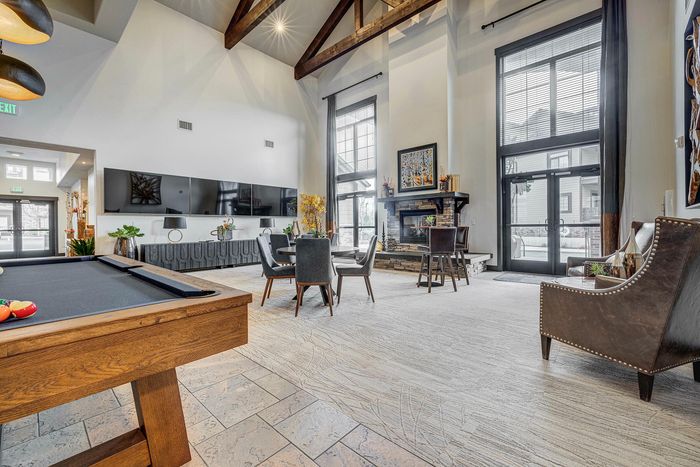 Luxurious modern living area showcasing high vaulted ceilings, a cozy fireplace, elegant decor, and a chic pool table for entertainment.