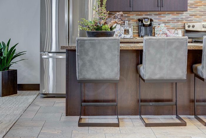 Chic modern kitchen with a sleek stainless steel refrigerator, stylish bar stools, and a trendy backsplash.