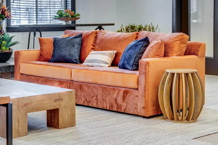 Inviting contemporary living room featuring a plush orange sofa with stylish cushions, complemented by a wooden coffee table and modern decor.