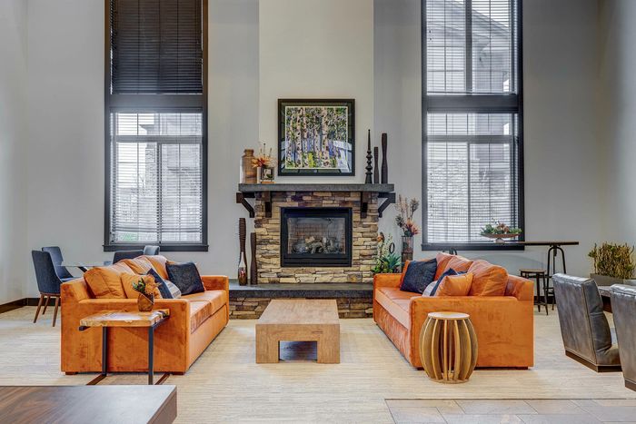Inviting living room with stylish stone fireplace, vibrant orange sofas, and elegant decor creating a cozy ambiance.