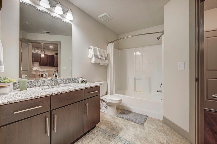 Modern bathroom featuring a sleek granite countertop, polished fixtures, and a bright, inviting shower area.