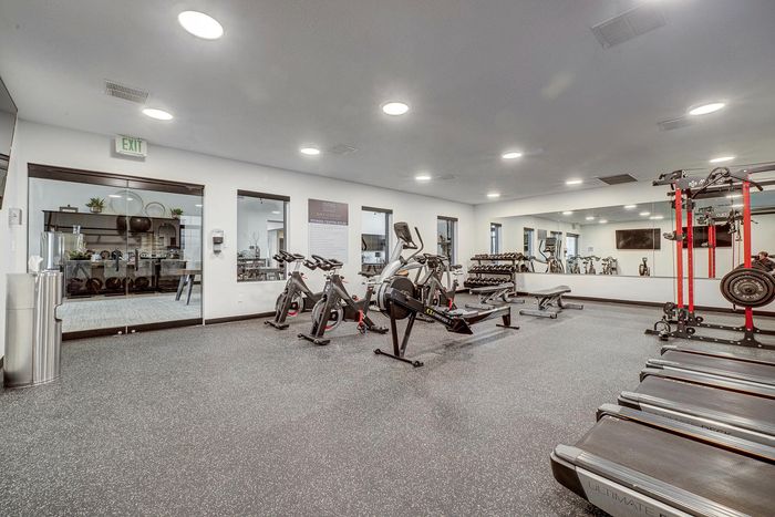 Modern fitness center with state-of-the-art equipment, including treadmills, stationary bikes, weights, and mirrored walls for an invigorating workout experience.