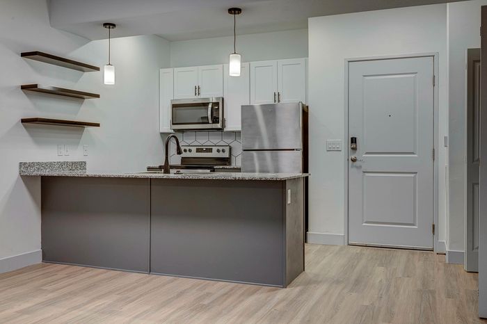 Modern kitchen with sleek countertops, stainless steel appliances, and elegant pendant lighting, showcasing contemporary design.