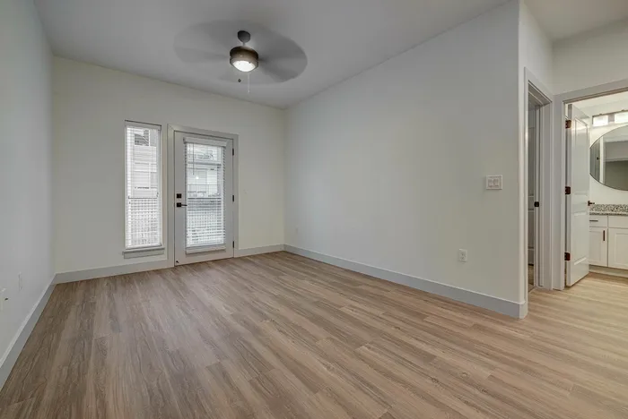 Bright, modern room with elegant wood flooring, a ceiling fan, and direct access to a stylish bathroom, ideal for comfortable living.
