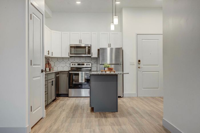 Sleek modern kitchen with stainless steel appliances, elegant white cabinets, and hexagonal tile backsplash, perfect for contemporary living.