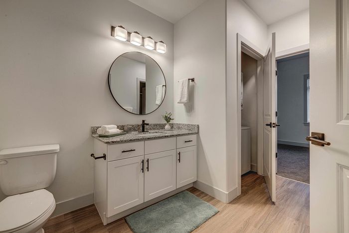 Elegant bathroom featuring a chic granite countertop vanity, modern round mirror, and ambient lighting that creates a serene atmosphere.
