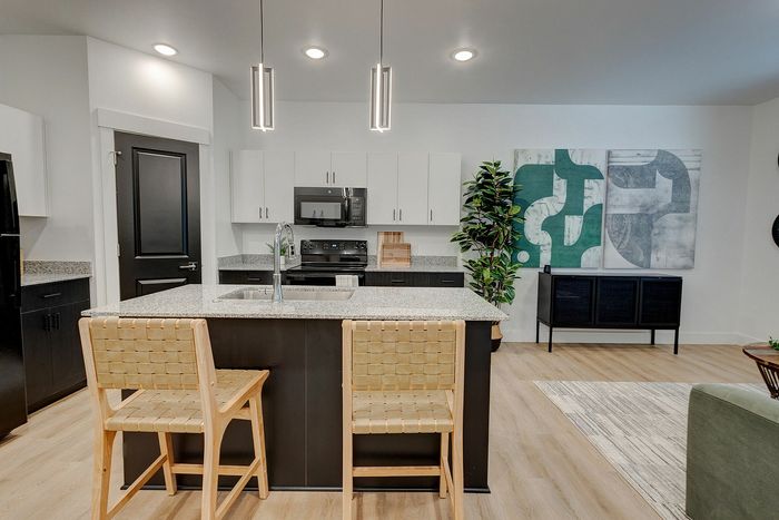 Modern kitchen with sleek cabinetry, granite countertops, and stylish island seating, set in an open-concept living space with chic decor.