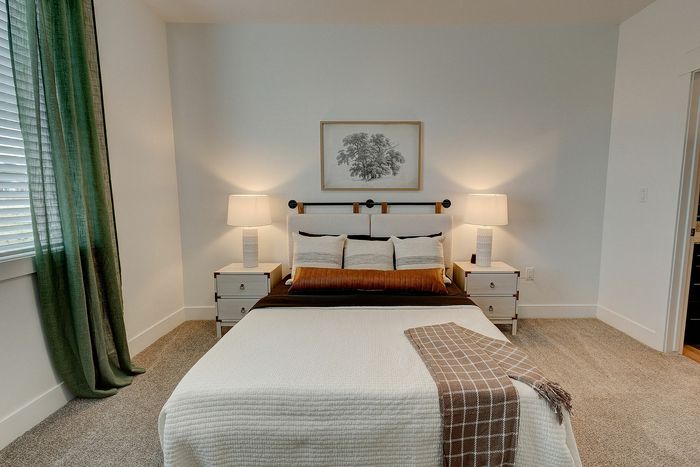 Inviting bedroom with a cozy bed, elegant side tables, soft lighting, and a serene wall art piece.