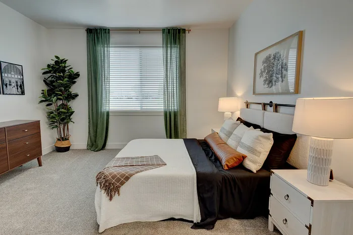 Elegant bedroom with cozy bed, stylish green curtains, tasteful wall art, and warm bedside lighting.