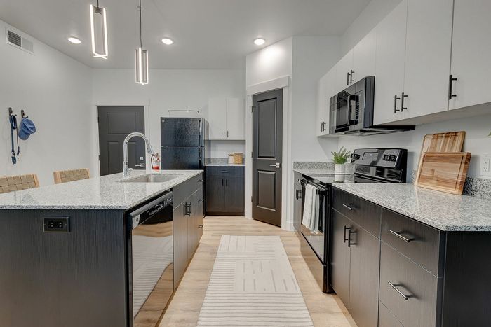 Modern kitchen design featuring sleek black cabinetry, granite countertops, and stylish pendant lighting.