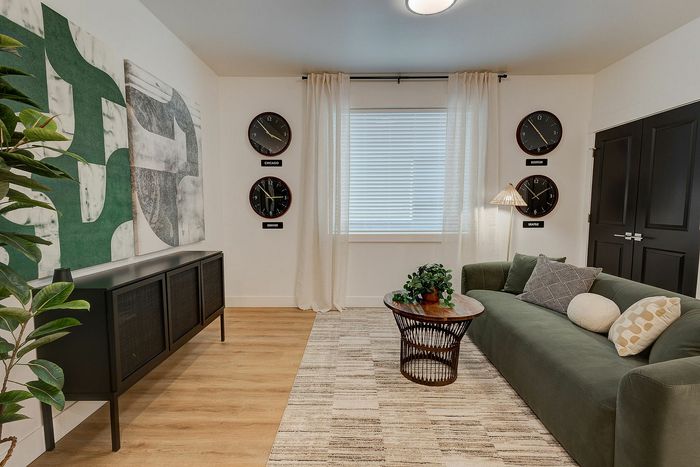 Chic living room with modern green sofa, stylish wall art, global city clocks, and elegant decor accents.