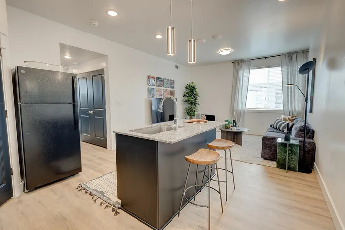 Modern open-concept kitchen and living room with chic decor and natural light, featuring a stylish island and cozy seating.