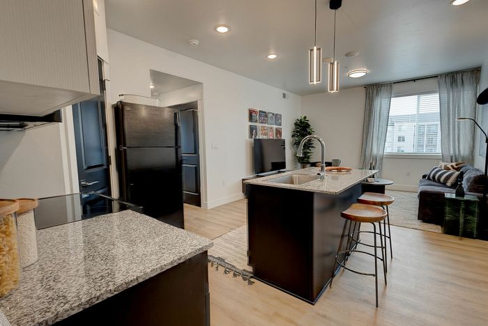 Modern open-concept kitchen and living room with granite countertops, stylish lighting, and cozy seating area.