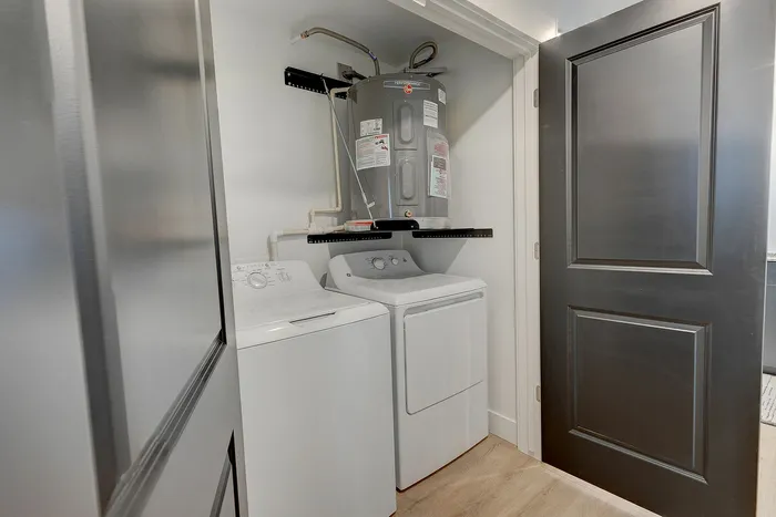 Modern laundry room with sleek washer, dryer, and efficient water heater in a stylish apartment setting.