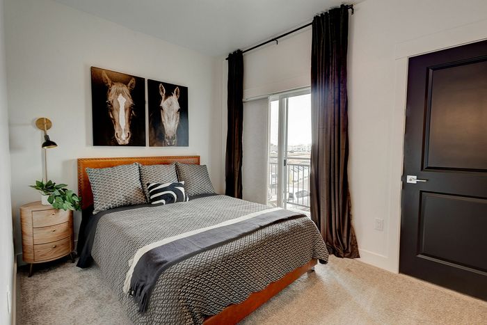 Elegant bedroom with stylish decor, featuring a cozy bed, modern side table, chic wall art, and a private balcony view.