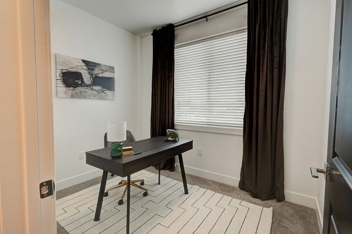 Chic home office with a sleek modern desk, cozy chair, and large window offering natural light.