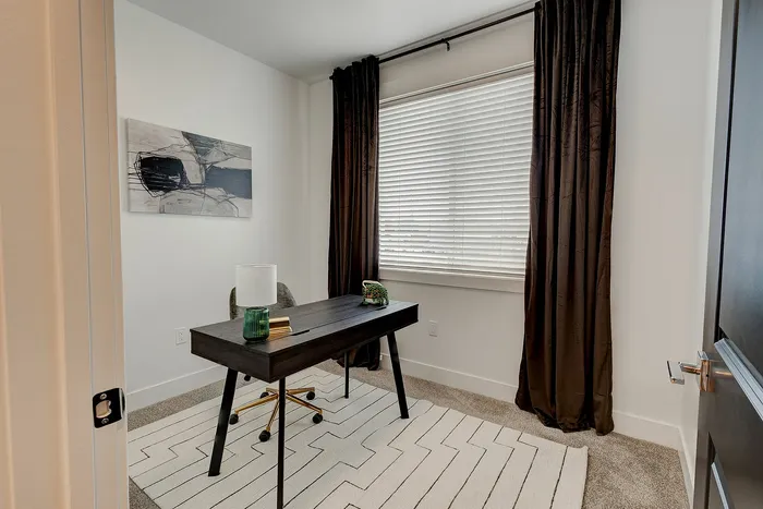 Chic home office with modern desk, stylish art, and natural light from large window with elegant curtains.