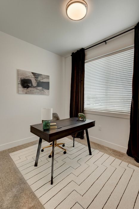 Modern home office with sleek black desk, cozy carpet, and large window for natural light. Ideal for productivity and inspiration.