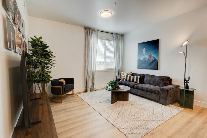 Chic living room with hardwood floors, cozy dark gray sofa, modern art, and abundant natural light.