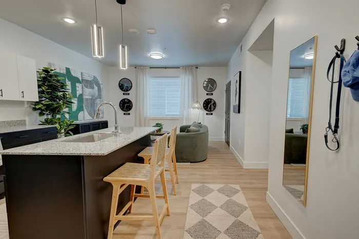 Modern apartment kitchen with sleek granite countertops, stylish pendant lighting, and a cozy living area with elegant decor.