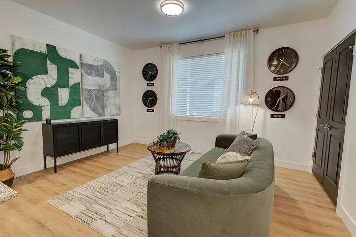 Chic living room with plush green sofa, stylish wall art, and elegant decor, complemented by wooden accents and modern clocks.