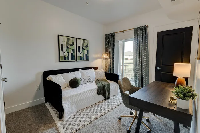 Cozy home office with elegant decor, featuring a comfortable sofa, stylish desk, and large window with chic curtains.