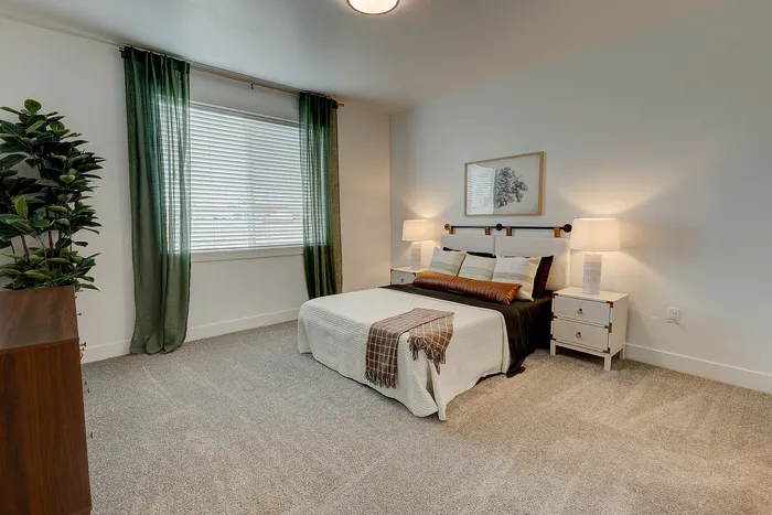 Inviting bedroom with soft carpeting, elegant green drapes, and modern decor creates a cozy atmosphere.