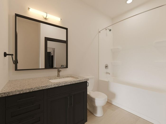 Elegant bathroom featuring a sleek granite countertop, modern fixtures, and a pristine bathtub with soft lighting.
