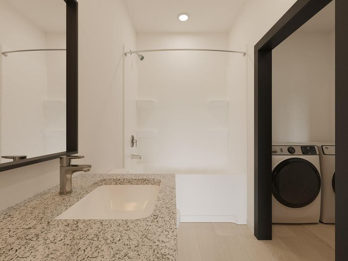 Elegant bathroom with a sleek granite countertop, modern fixtures, and a concealed washer-dryer unit.