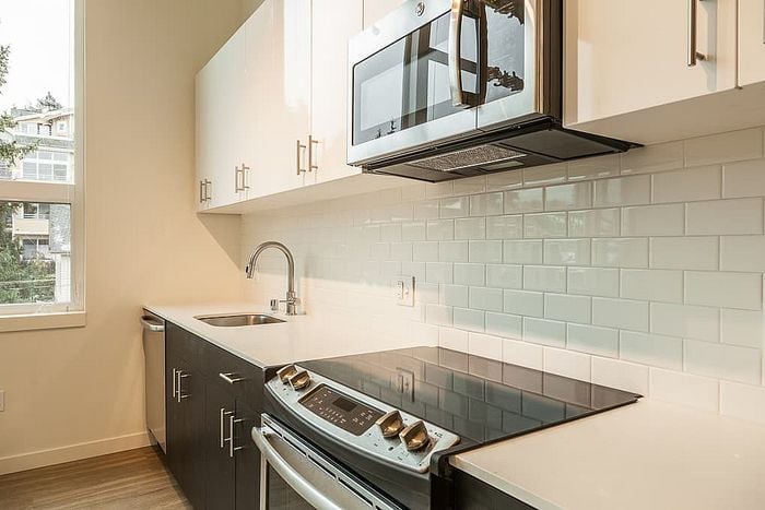Modern kitchen with sleek appliances, elegant cabinetry, and a stylish tile backsplash, filled with natural light.