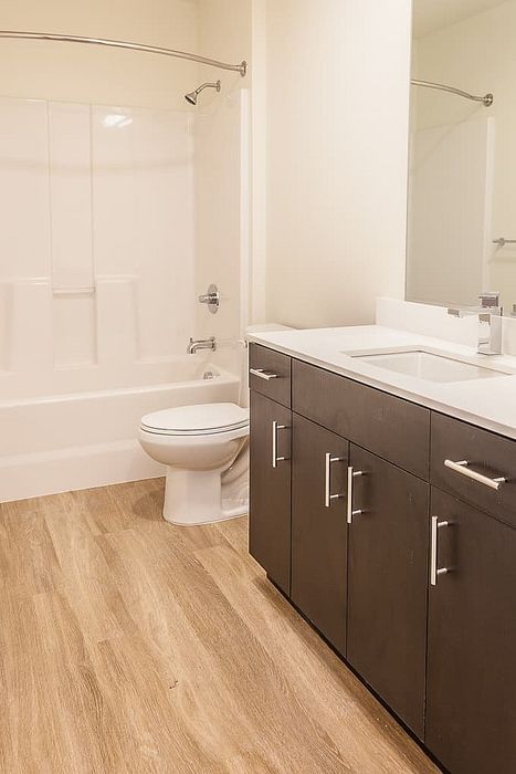 Elegant bathroom with modern fixtures, sleek dark wood cabinetry, and pristine white bathtub featuring a stylish curved shower rod.