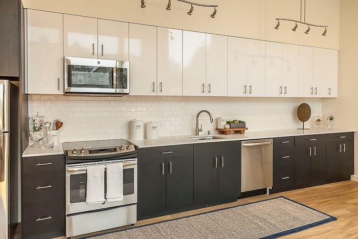 Contemporary kitchen with sleek two-tone cabinetry, modern appliances, and elegant lighting fixtures.