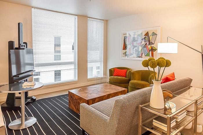 Chic and cozy living room with stylish modern furniture, featuring large windows, vibrant artwork, and a sleek TV setup, offering a welcoming ambiance.