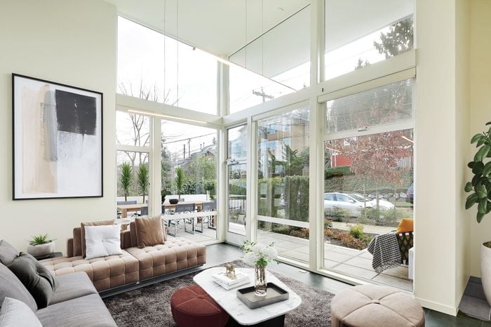 Bright and elegant living room with floor-to-ceiling windows, modern furniture, and a cozy ambiance inviting natural light and garden views.