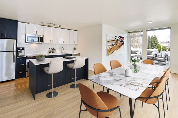 Modern open-concept kitchen and dining area with sleek marble table, elegant seating, and access to a cozy outdoor patio.