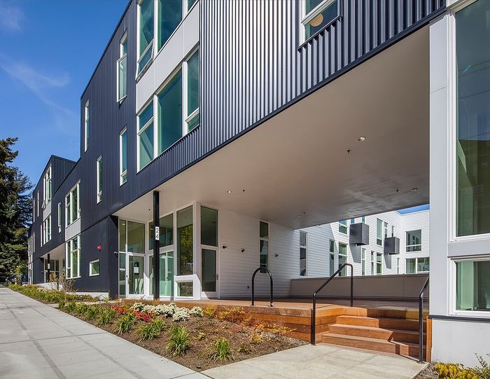Contemporary apartment building with sleek design, large windows, and landscaped entryway.